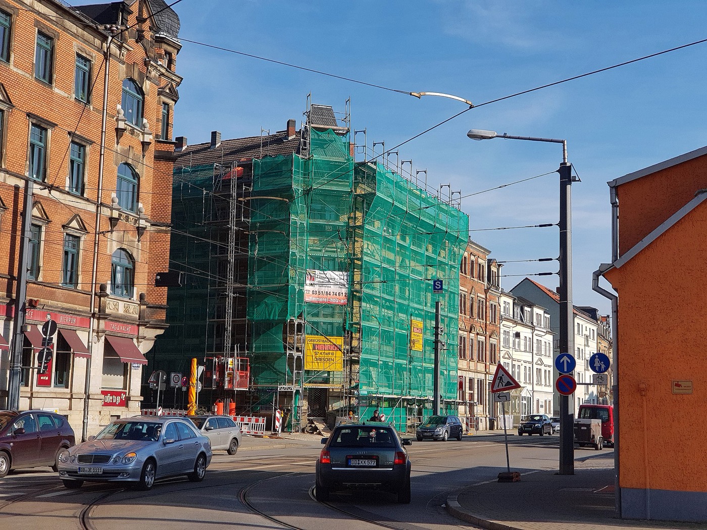 In Gerüst und grünes Schutznetz gehülltes Gründerzeit-Wohnhaus an einer Straßenecke während der Sanierung.