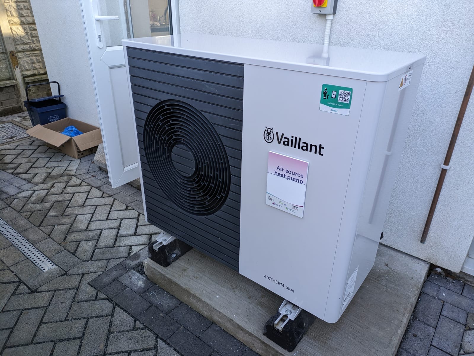 Außengerät einer Luftwärmepumpe an der Wand eines Wohnhauses.